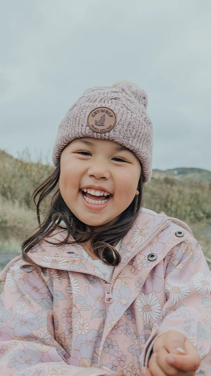 Girl wearing blush sparkle pom pom beanie.
