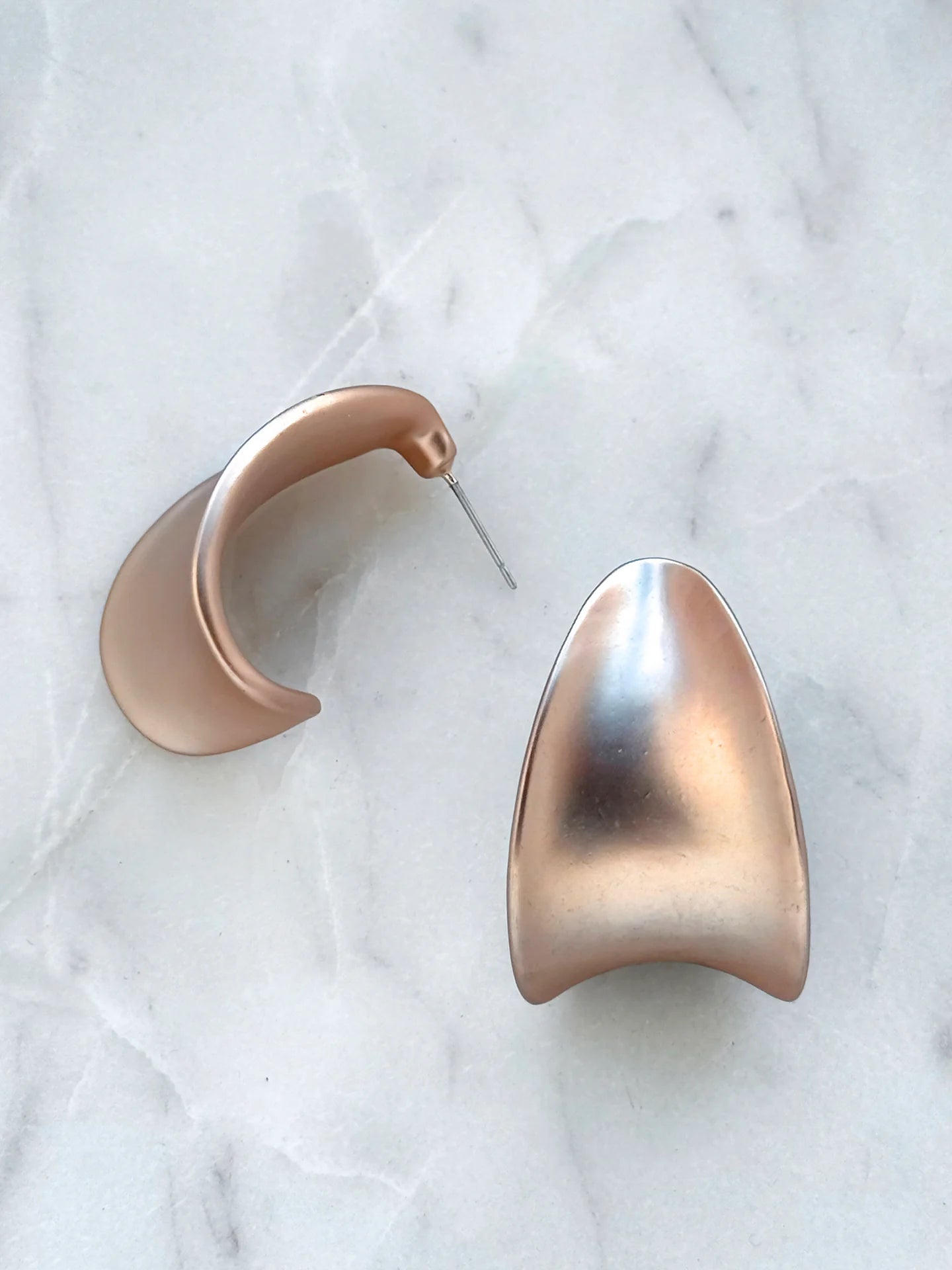 Pair of matte gold modern geometric earrings on white marble background