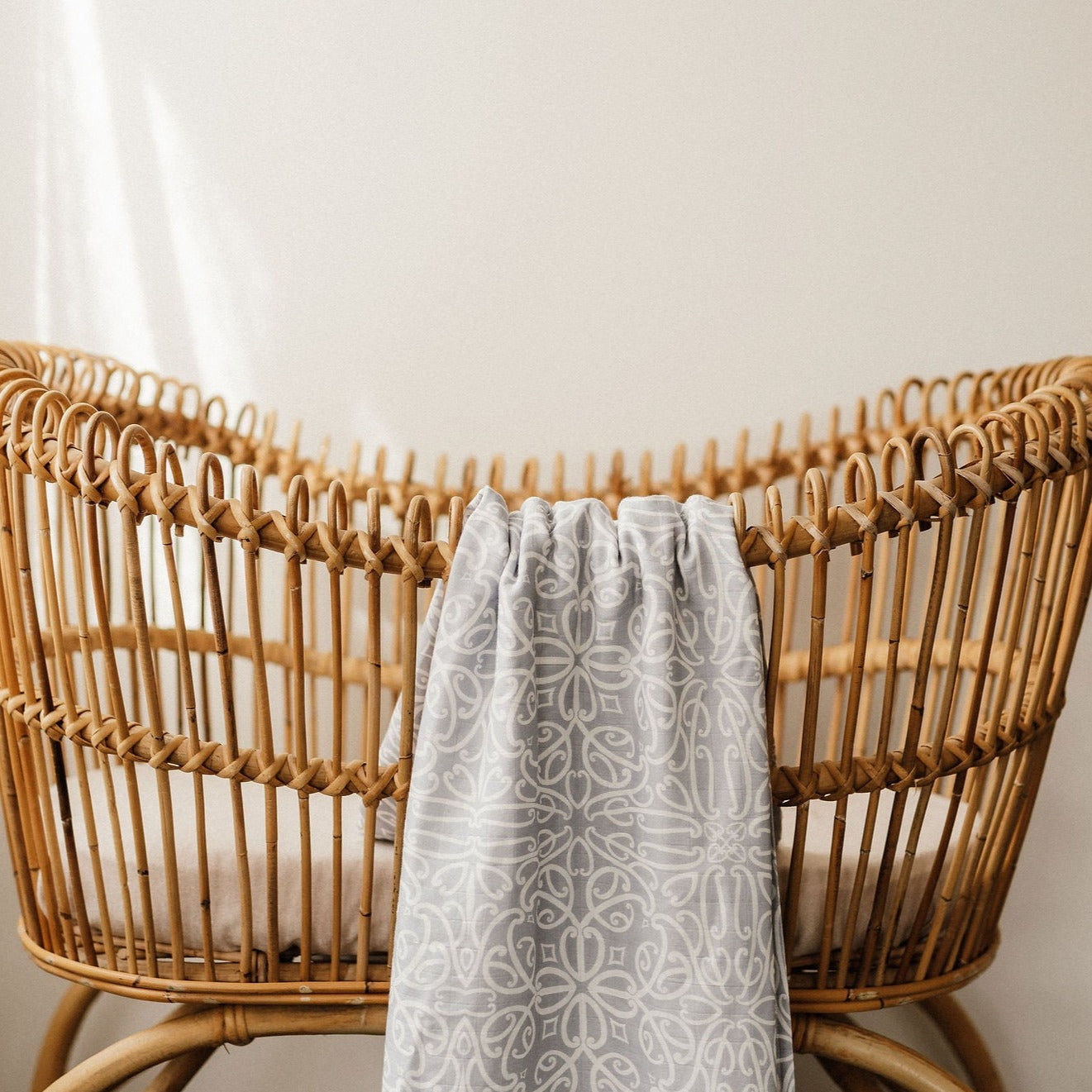 Patterned grey linen blanket draped over a natural rattan chair