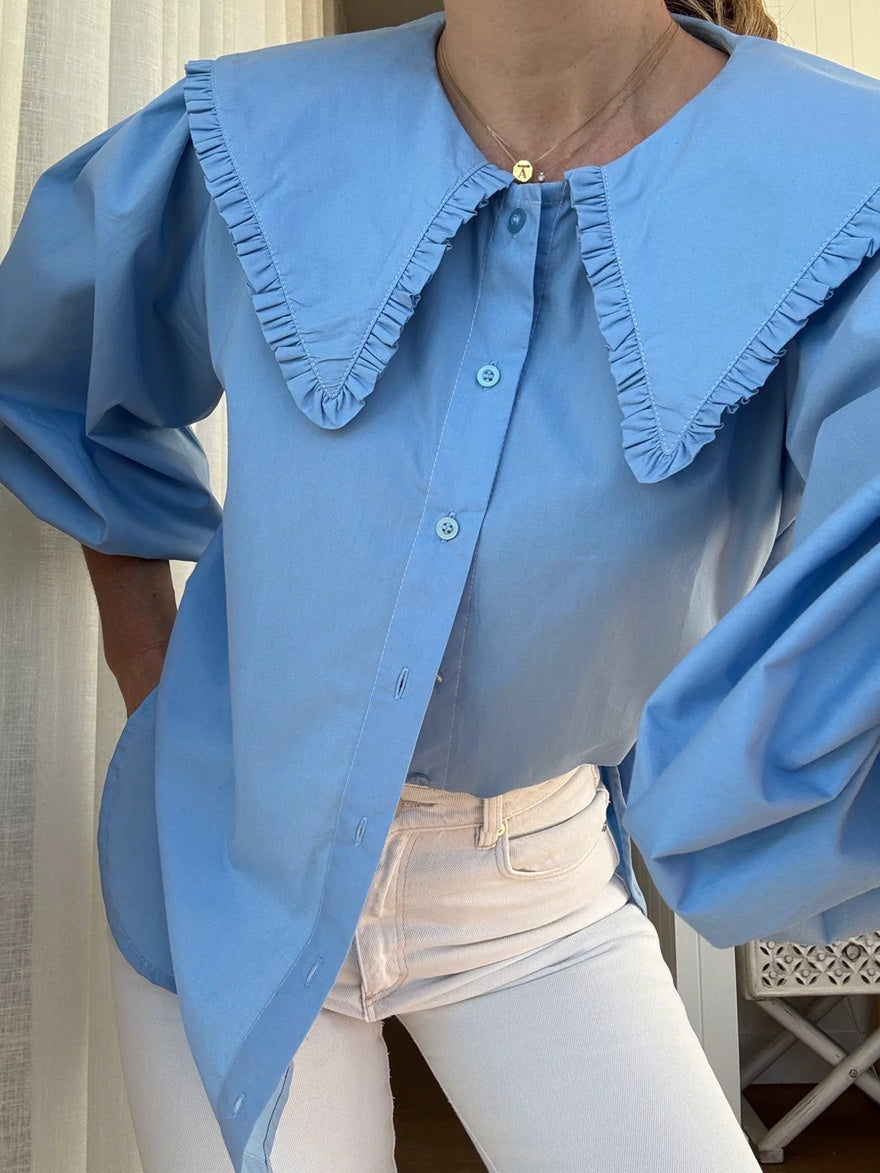 Woman wearing a blue linen shirt with ruffled oversized collar and puff sleeves