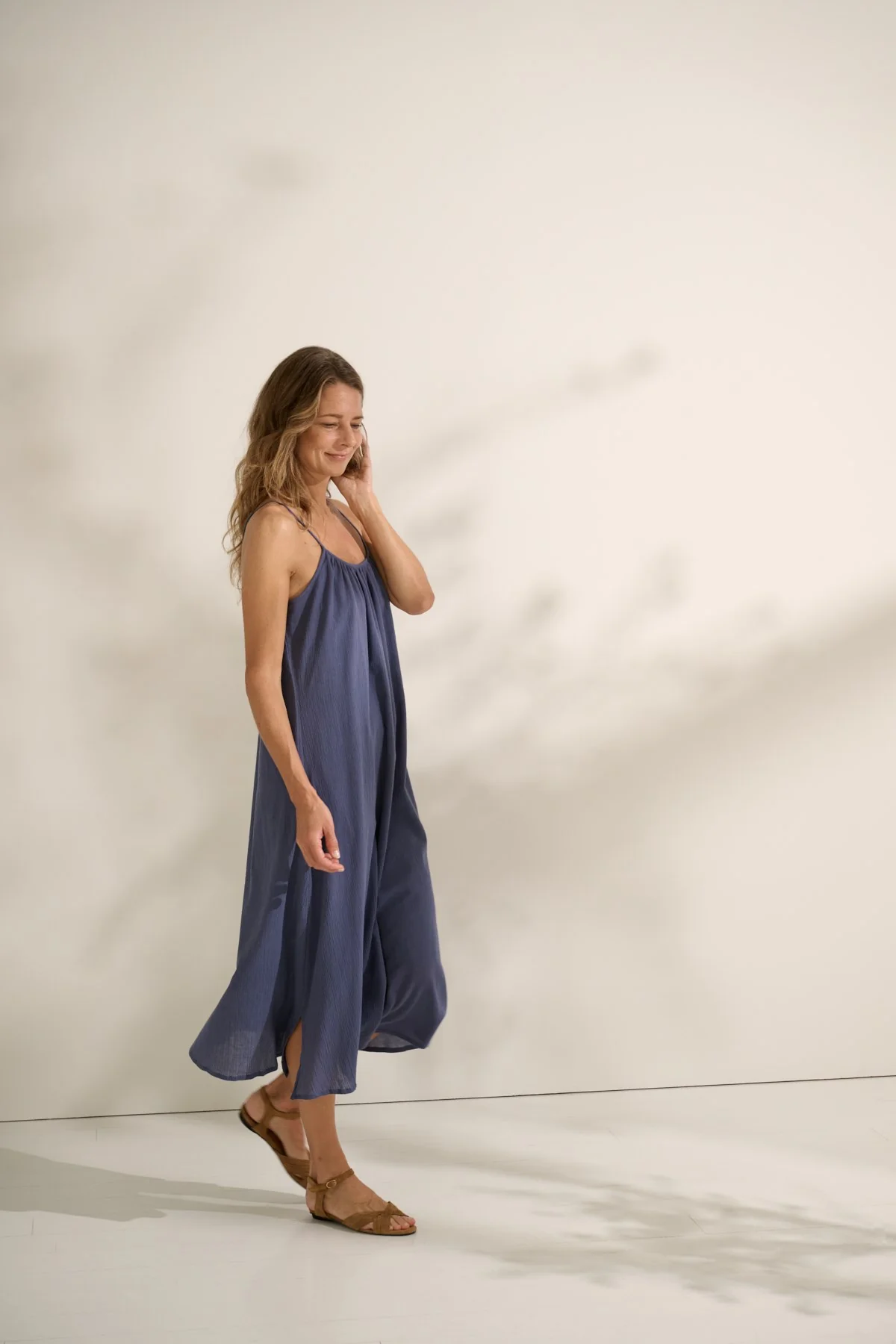 Woman wearing blue gauze. midi sundress side view.