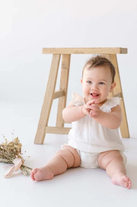 Child wearing white cotton muslin blouse with white bloomer sitting down