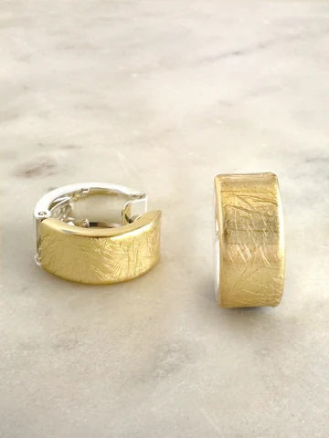 Gold and silver textured hoop earrings on a marble surface