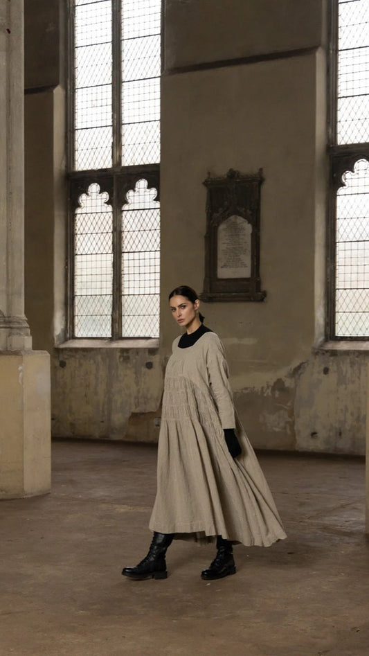Woman wearing heavyweight linen dress with square neck line.