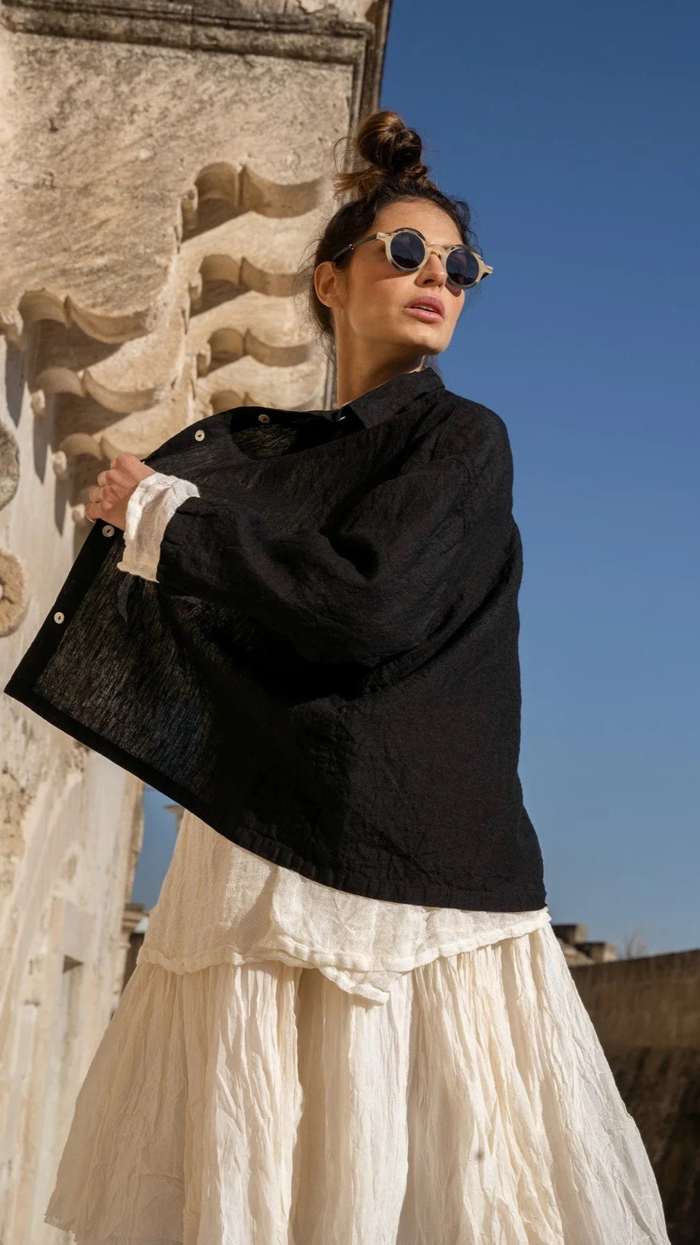 Woman wearing black linen shirt and cream linen dress, outdoor, sunny day, sunglasses