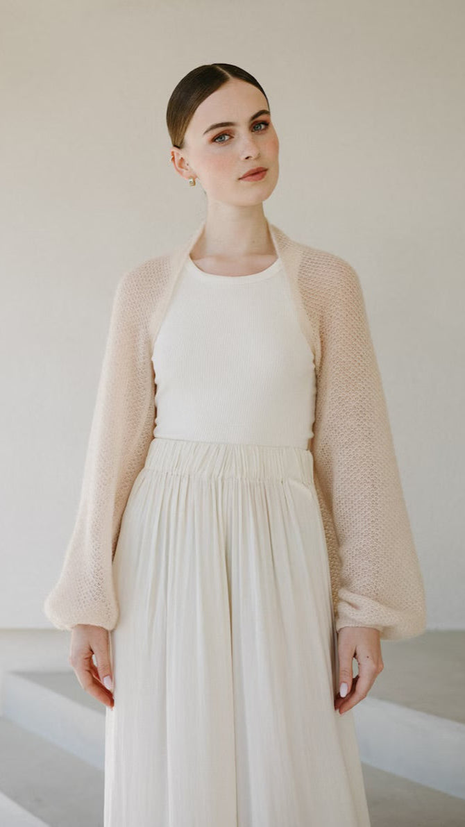 Woman wearing sand mohair bolero with puffed sleeve.
