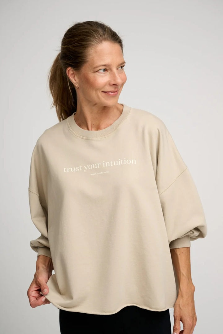 Woman wearing ecru oversized sweat shirt with boxy fit and voluminous sleeves.