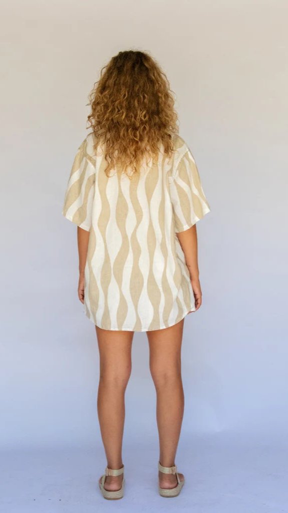 Back view of woman in beige and white striped linen shirt with short sleeves