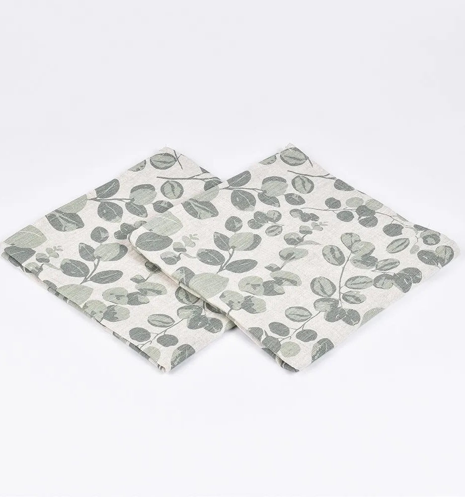 Two linen napkins with green eucalyptus leaf print on a white background