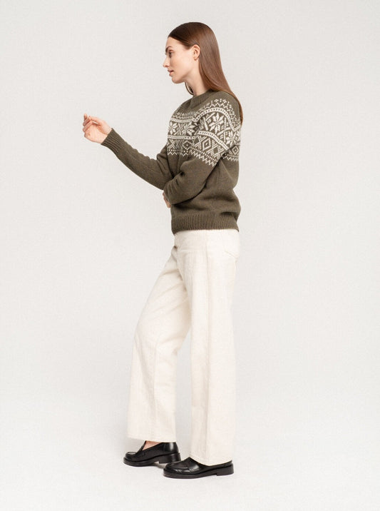 Woman in a patterned merino sweater and wide-leg linen pants, side view, studio background
