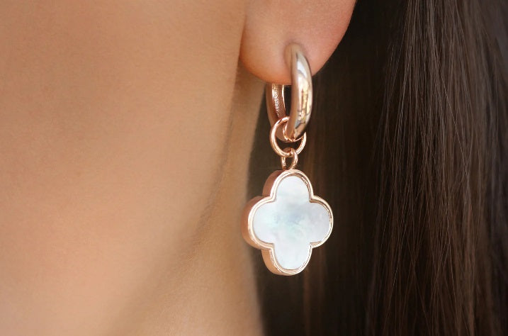 Gold hoop earring with mother of pearl clover pendant worn on ear