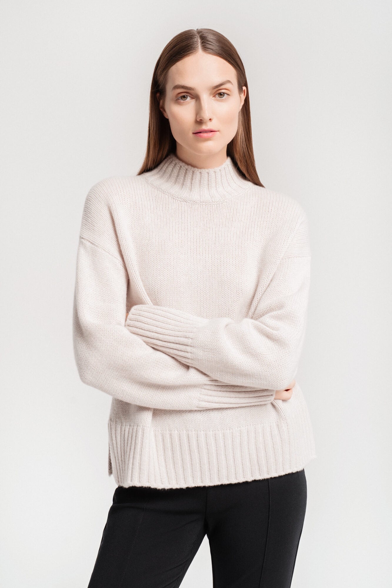 Woman wearing a relaxed sweater with high neckline and side splits.