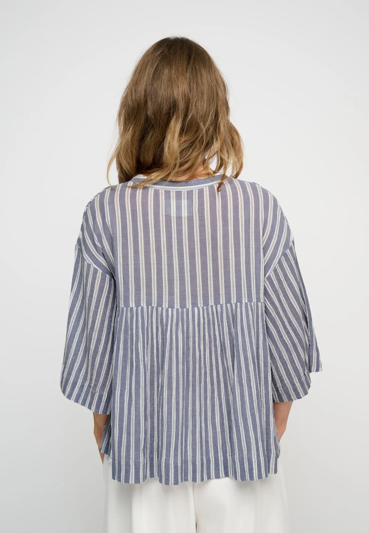 Woman wearing blue stripe peplum shirt back view.