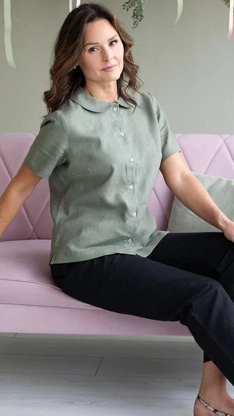 Model seated wearing khaki linen short sleeve shirt with peter pan collar