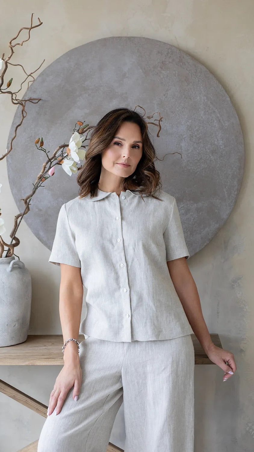 Woman wearing natural linen short sleeve shirt with peter pan collar and short sleeve.