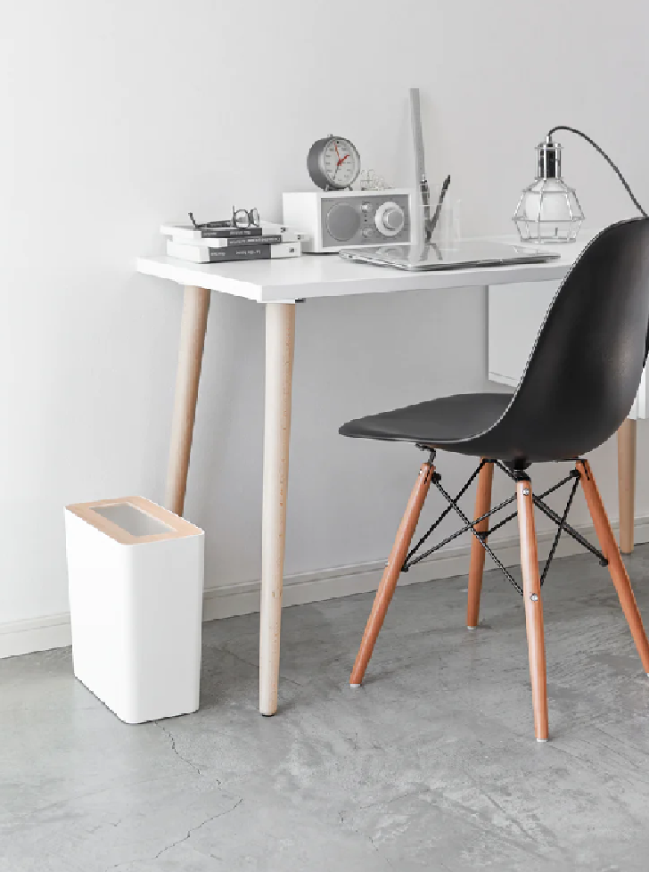 Modern white rectangular rubbish bin beside minimalist desk and black chair in home office