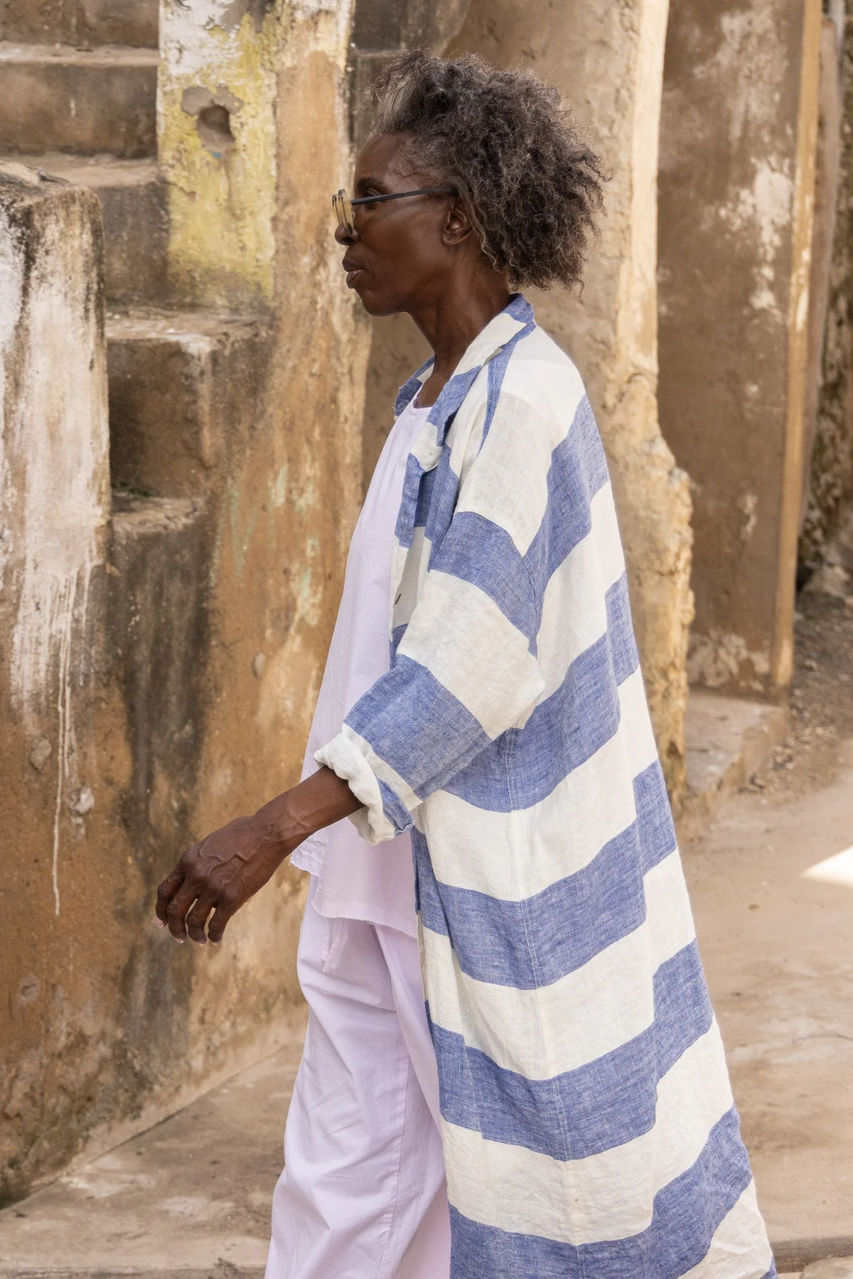 Woman wearing blue and white striped linen shirt and white linen pants outdoors