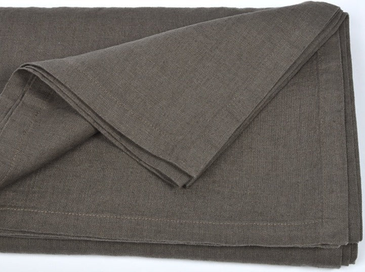 Folded dark brown linen tablecloth with visible stitched edges