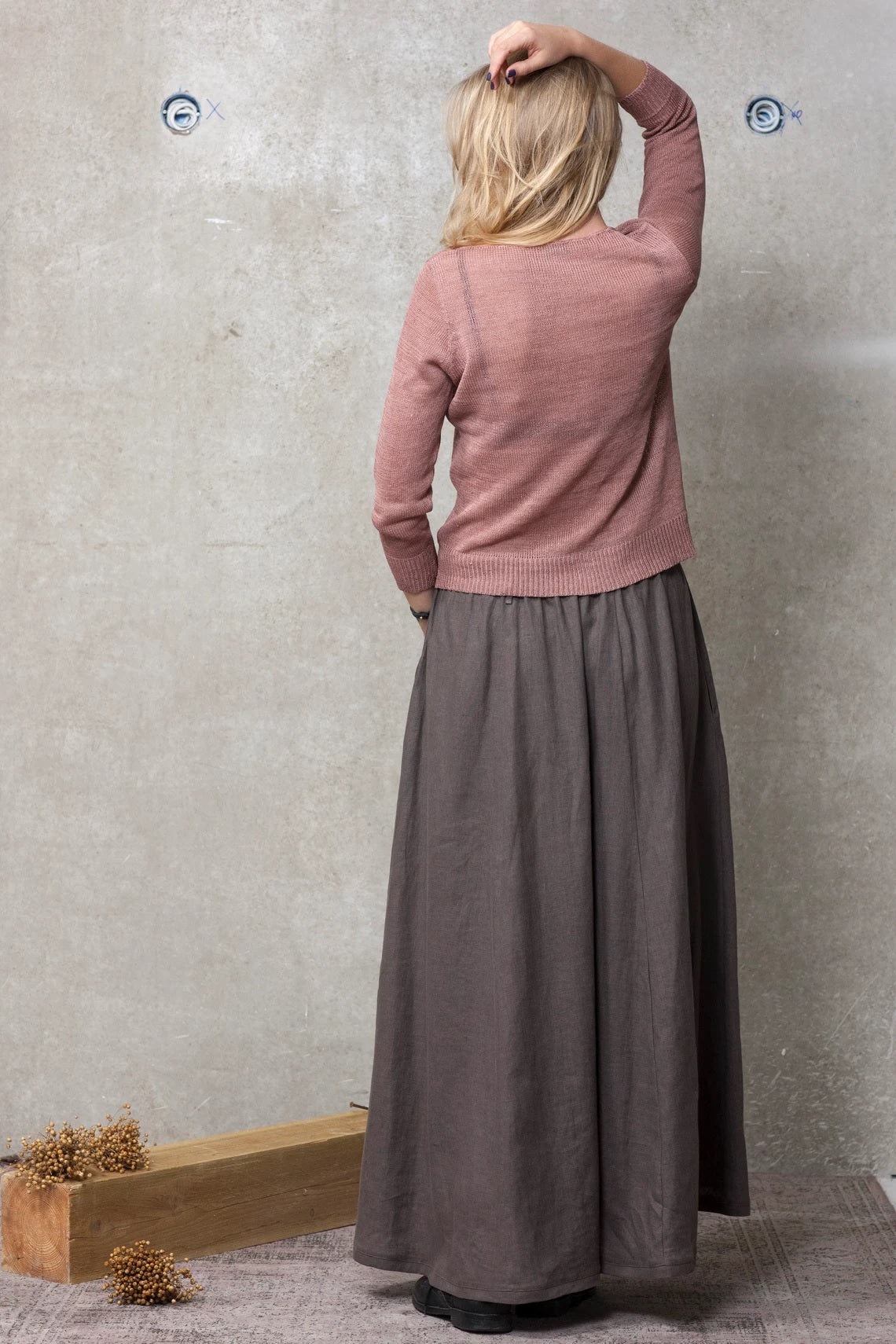 Woman wearing a pink sweater and brown linen maxi skirt, back view, casual setting
