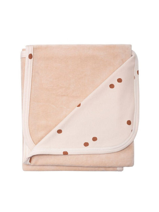 Folded beige blanket with brown polka dots and soft fabric texture
