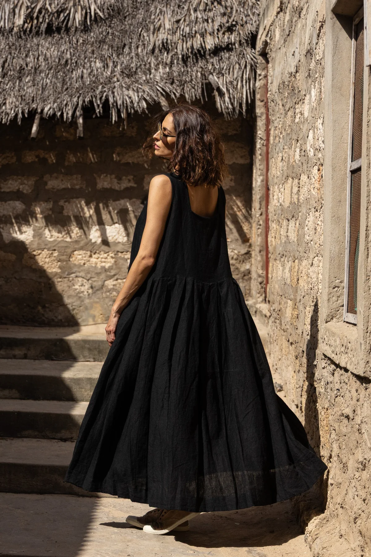 Woman wearing black linen sun dress back view.