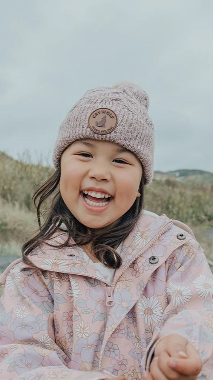 Girl wearing blush sparkle pom pom beanie.