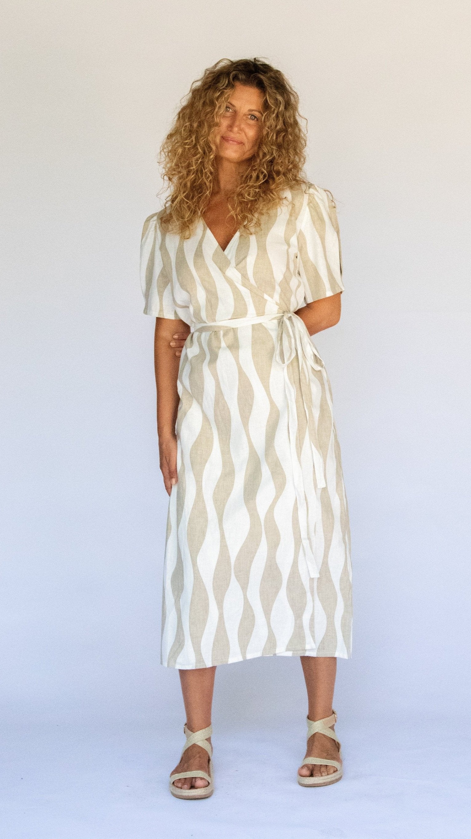 Woman wearing wrap midi dress in island stripe white and beige