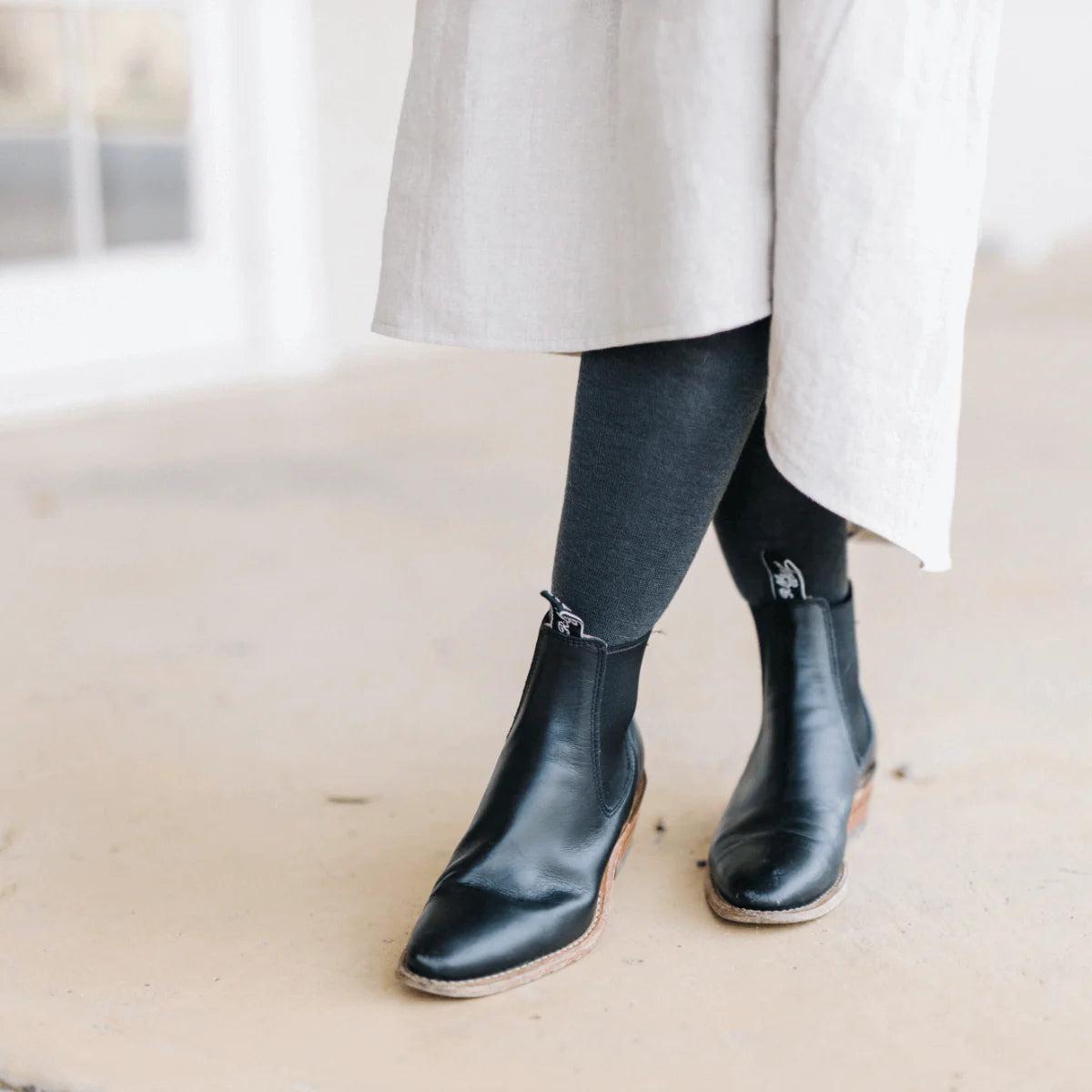 Woman wearing charcoal merino flat knit tights.
