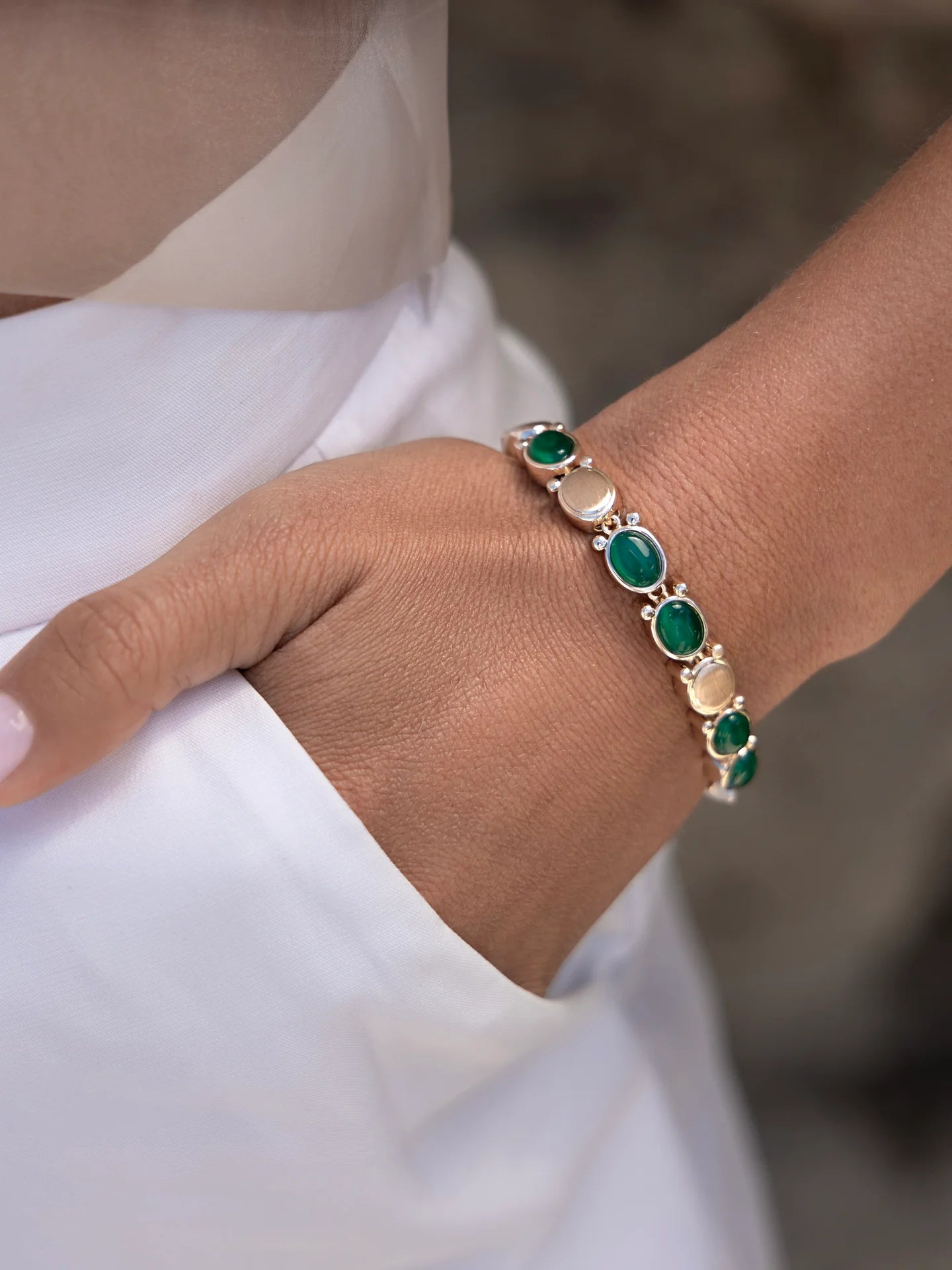 Woman wearing green cat eye bracelet with brushed yellow gold.