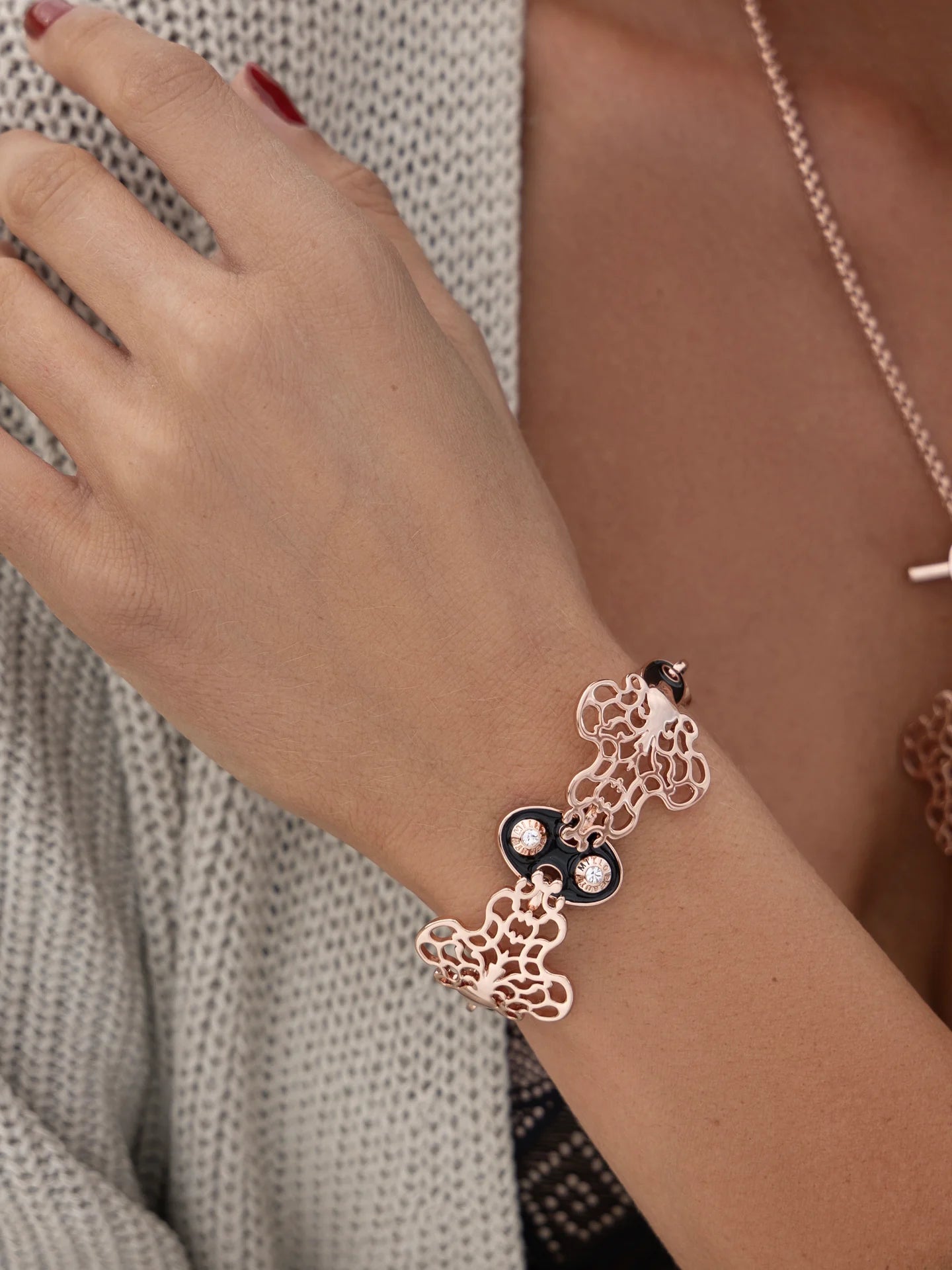 Woman wearing a bracelet with black enamel and rose gold plating in a decorative style.
