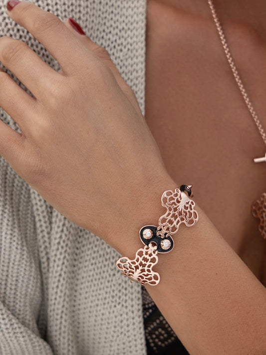Woman wearing a bracelet with black enamel and rose gold plating in a decorative style.
