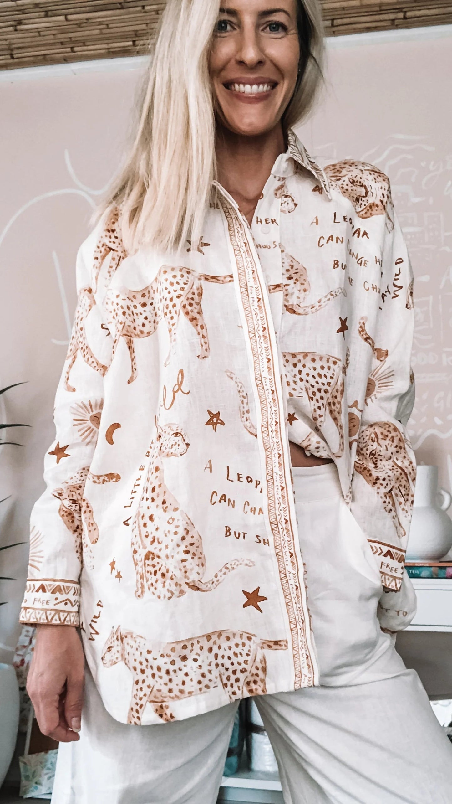 Woman wearing leopard print linen shirt with buttoned front and long sleeve.