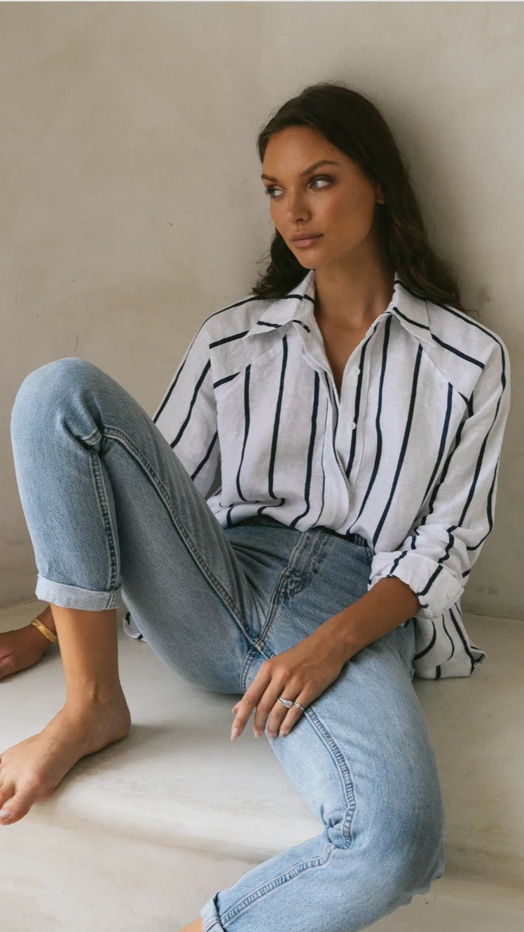 Woman wearing striped blue linen shirt with buttoned front.