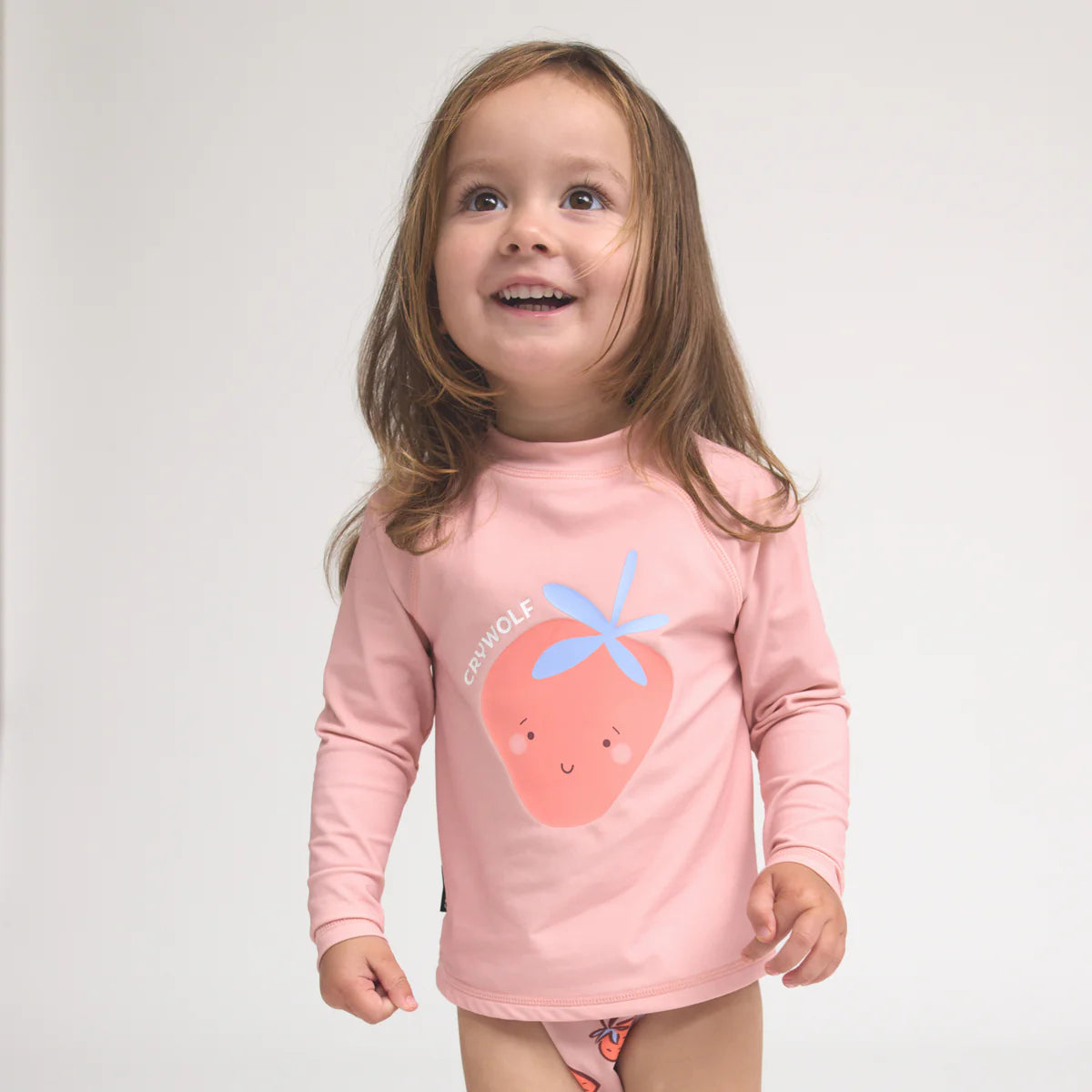 Young child in a pink long sleeve shirt with a cute fruit graphic and matching bottoms