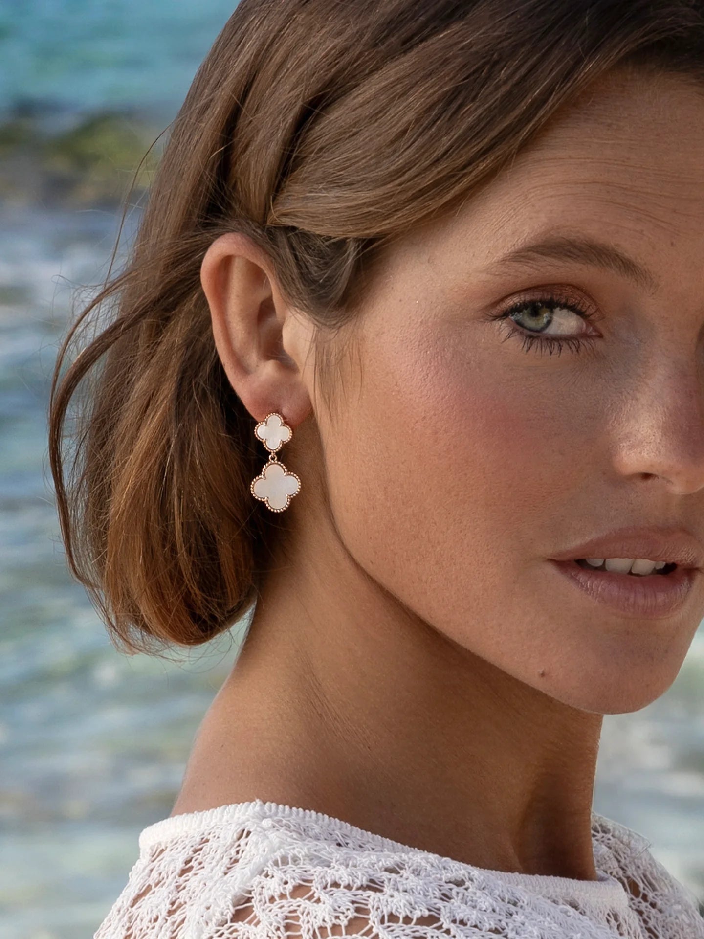 Woman wearing mother of pearl double drop earring in flower design.