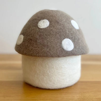 Felt mushroom decor with brown top and white spots on a wooden surface