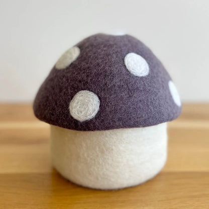 Handmade felt mushroom decor with purple cap and white spots on a wooden surface