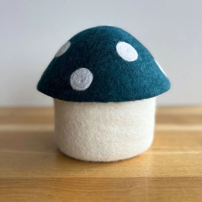 Felt mushroom decor with blue and white polka dot cap on wooden surface