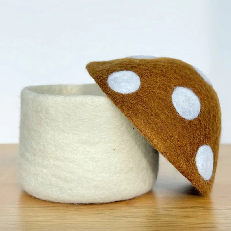 Felt storage box with removable brown and white polka dot mushroom cap lid on wood surface
