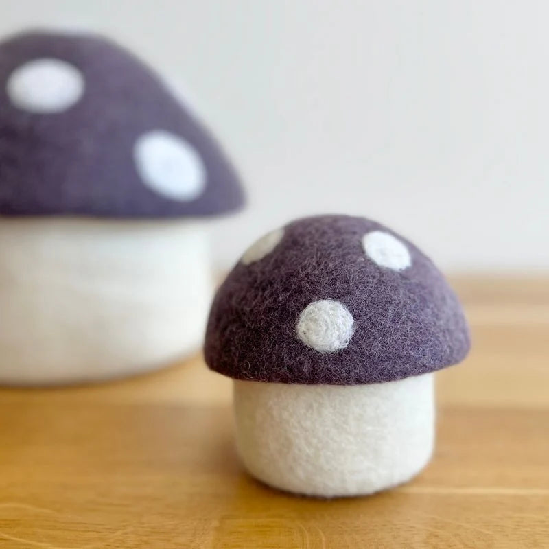 Felt mushroom decor with purple cap and white spots on a wooden surface