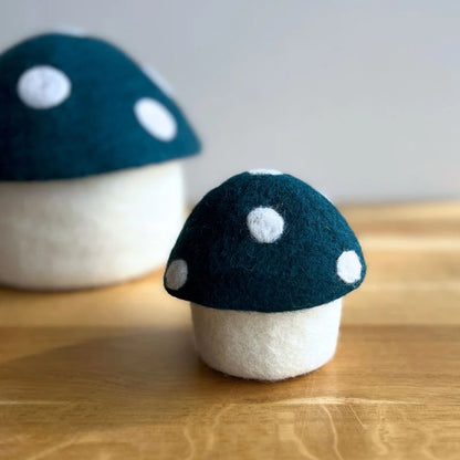Wool felt mushroom decor with dark blue cap and white polka dots on a wooden surface.