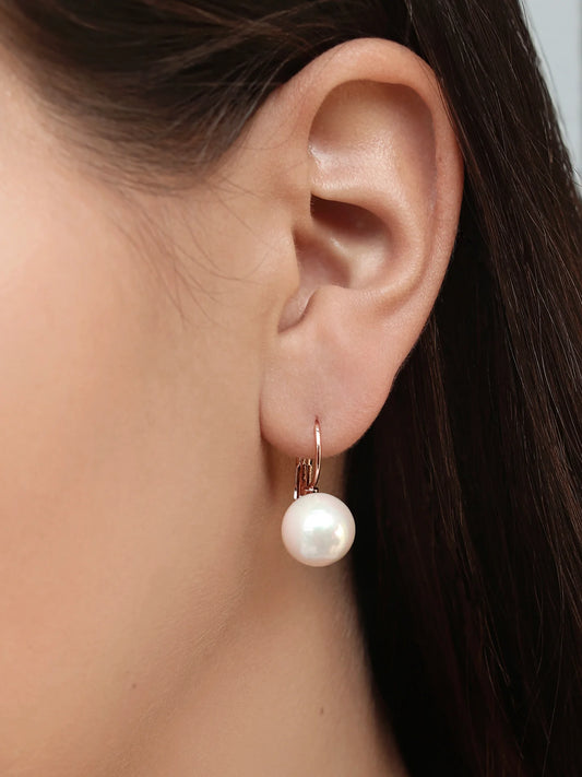 Woman wearing a gold hoop earring with a large white pearl drop