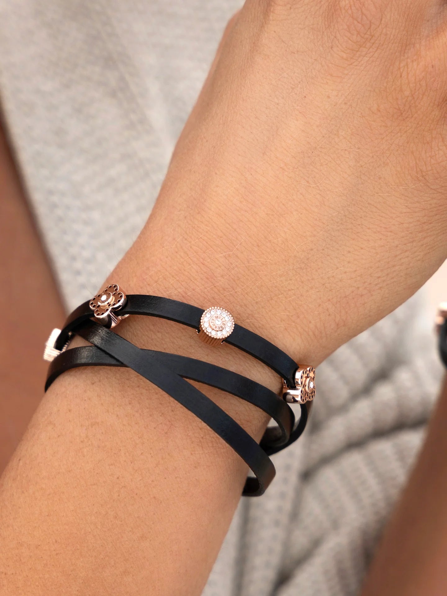 Black leather wrap bracelet with gold and crystal decorative charms on wrist