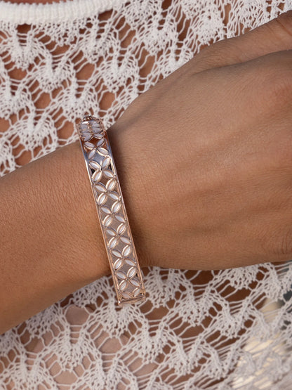 Rose gold patterned bangle bracelet on wrist, paired with a white lace top