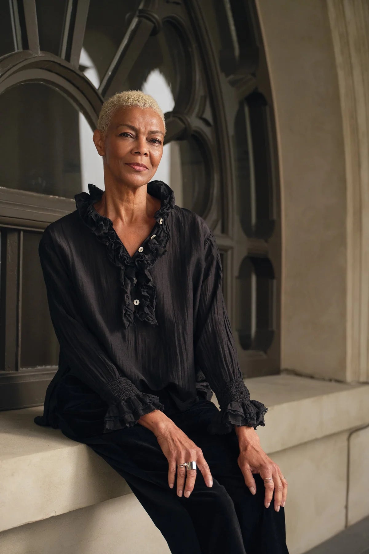 Woman wearing drapey silk blend shirt with ruffled collar, placket and cufffs.