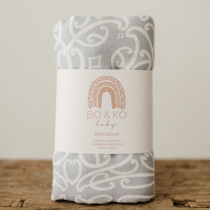 Grey and white patterned baby wrap with Bo & Ko Baby label, on wooden surface