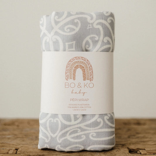 Grey and white patterned baby wrap with Bo & Ko Baby label, on wooden surface