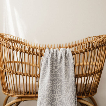 Patterned grey linen blanket draped over a natural rattan chair