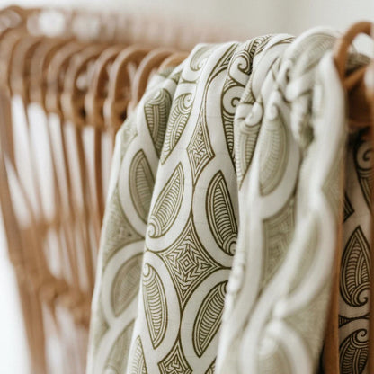 Patterned linen clothing with green geometric design on wooden hangers