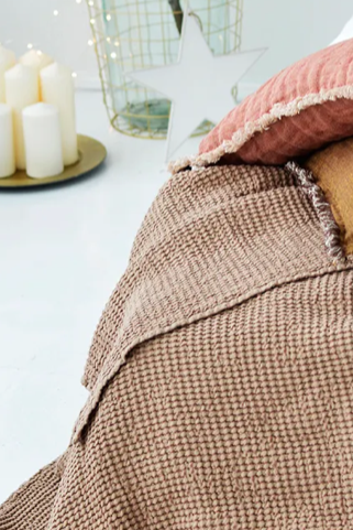 Textured linen blanket with two decorative linen cushions on a cozy bed